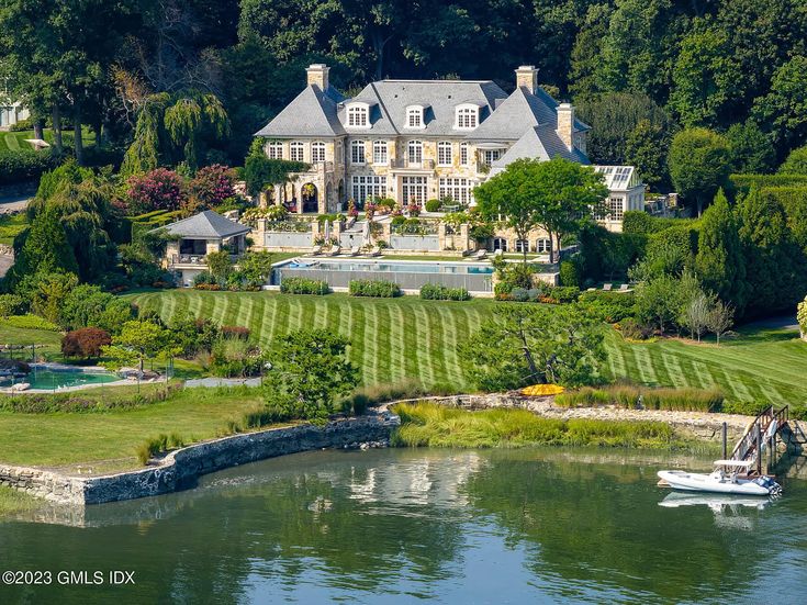 an aerial view of a large mansion with a boat on the water in front of it