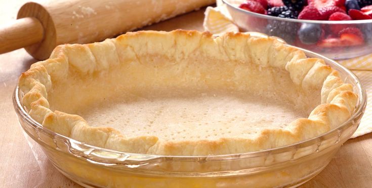 an uncooked pie crust next to a bowl of berries