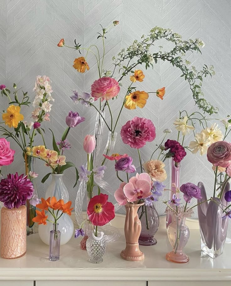 there are many different vases with flowers in them on the table next to each other