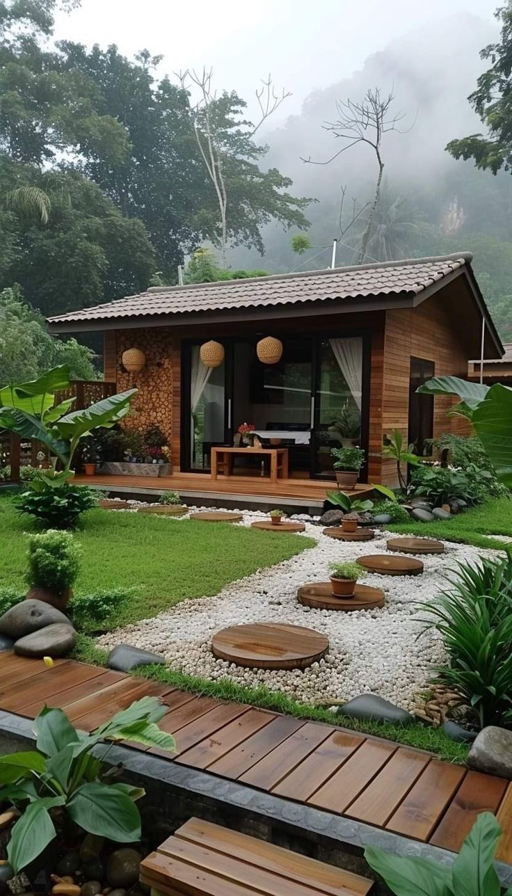 a small wooden house in the middle of a lush green field with trees and bushes