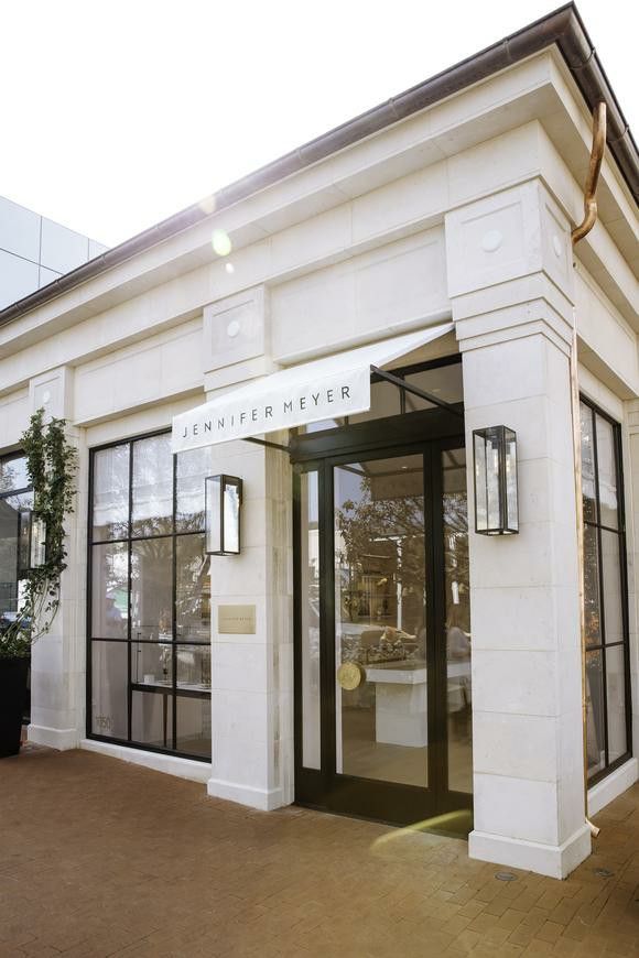 the front entrance to an office building with glass doors and potted plants on either side