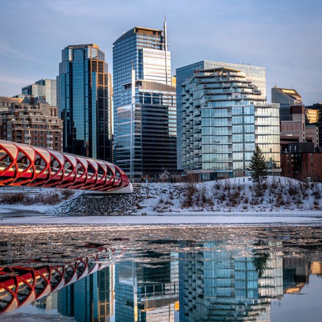 the city skyline is reflected in the still waters of the river that runs through it