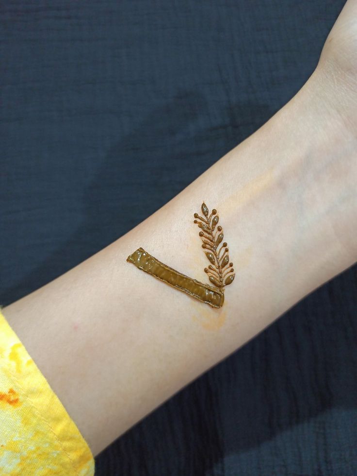 a person's arm with some gold paint on it and a stick in the middle