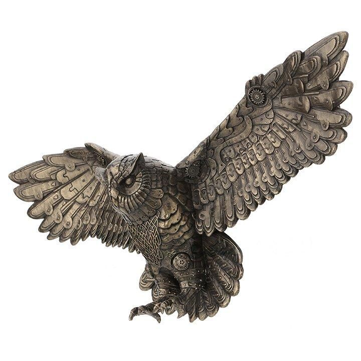 an owl figurine sitting on top of a white surface with its wings spread