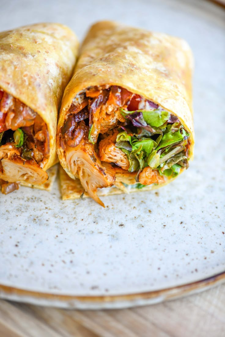 two burritos sitting on top of a white plate