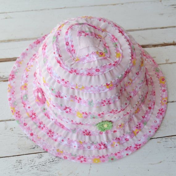 A beautiful child's summer hat in pastel bright pink and white. The hat features beautiful flower illustrations and some crochet style flowers in pink and orange.The ideal summer accessory for those little ones on the beach enjoying the sunshine.The hats are size 7 - 10, 3 - 6 & 1 - 2 years and we have limited availability of these.Made from:100% polyesterDimensions: 7 - 10 years3 - 6 years1 - 2 years Pink Summer Bucket Hat For Vacation, Playful Handmade Sun Hat For Summer, Pink Cap For Summer, Pink Brimmed Bucket Hat For The Beach, Pink Brimmed Bucket Hat For Beach, Playful Spring Hats For Play, Pink Summer Hat For Play, Fun Spring Sun Hat For Playtime, Fun Sun Hat For Spring Playtime