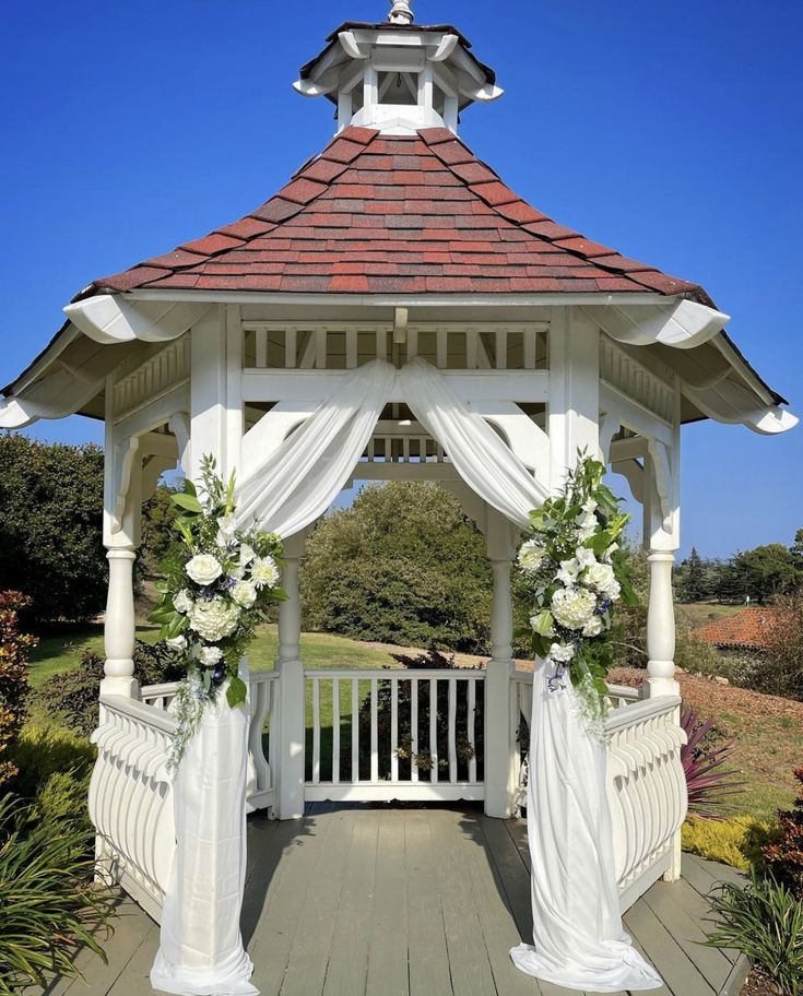 the gazebo is decorated with white flowers and greenery