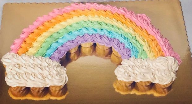 cupcakes with rainbow frosting and icing on them in the shape of a arch