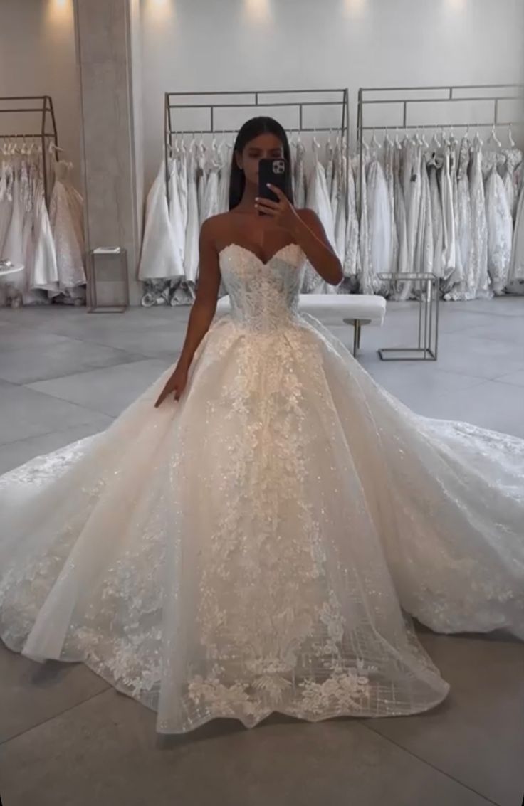 a woman in a wedding dress taking a selfie with her cell phone while she is looking at the camera