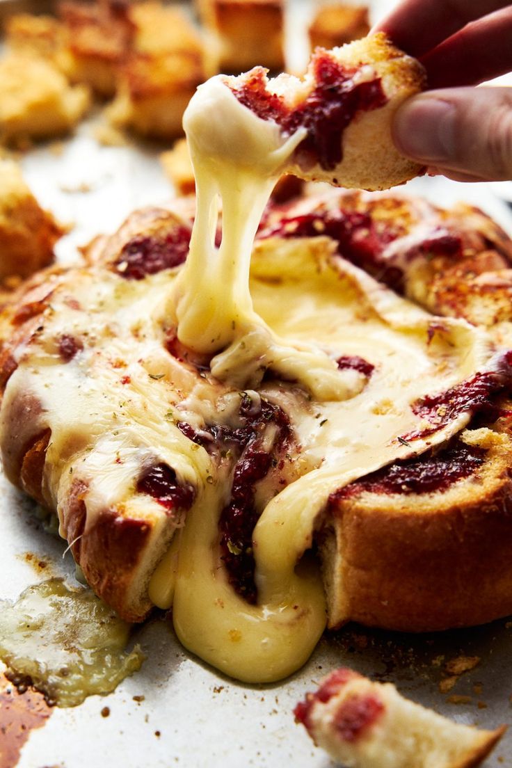 someone is dipping cheese on top of some breads with cranberry sauce and other toppings