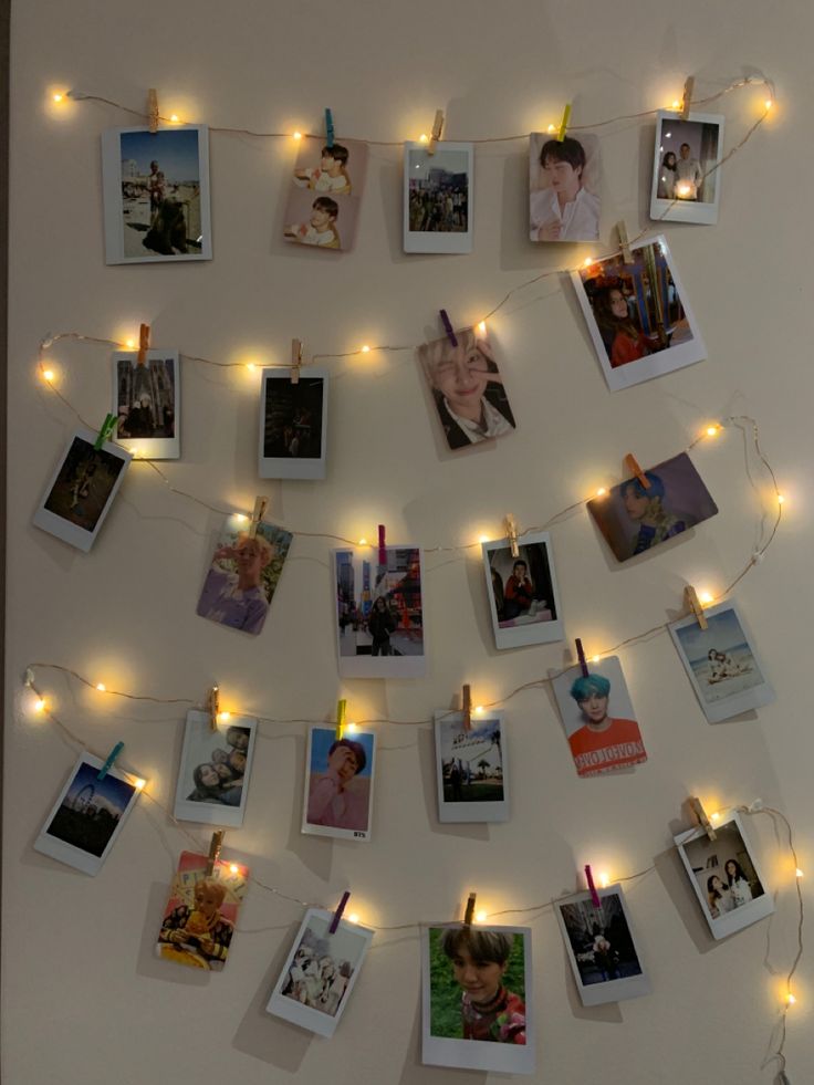 several polaroid pictures are hung on a string with lights strung from it and some photos have been pinned to the wall