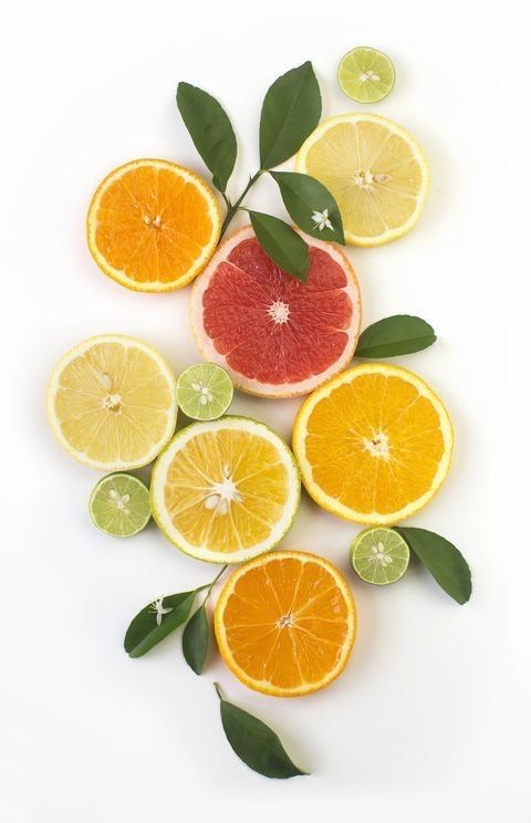 oranges, limes and grapefruit cut in half on a white background