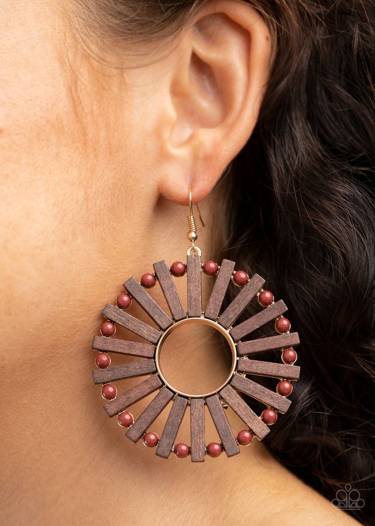 a close up of a woman's ear wearing wooden earrings with beaded details