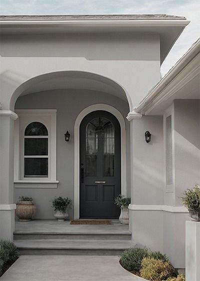 the front entrance to a house with potted plants on either side and an arched doorway