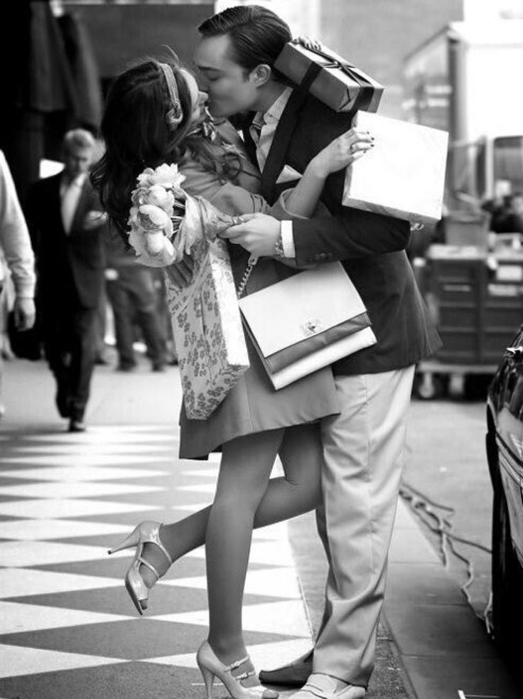 a man and woman kissing on the street with shopping bags over their heads in black and white