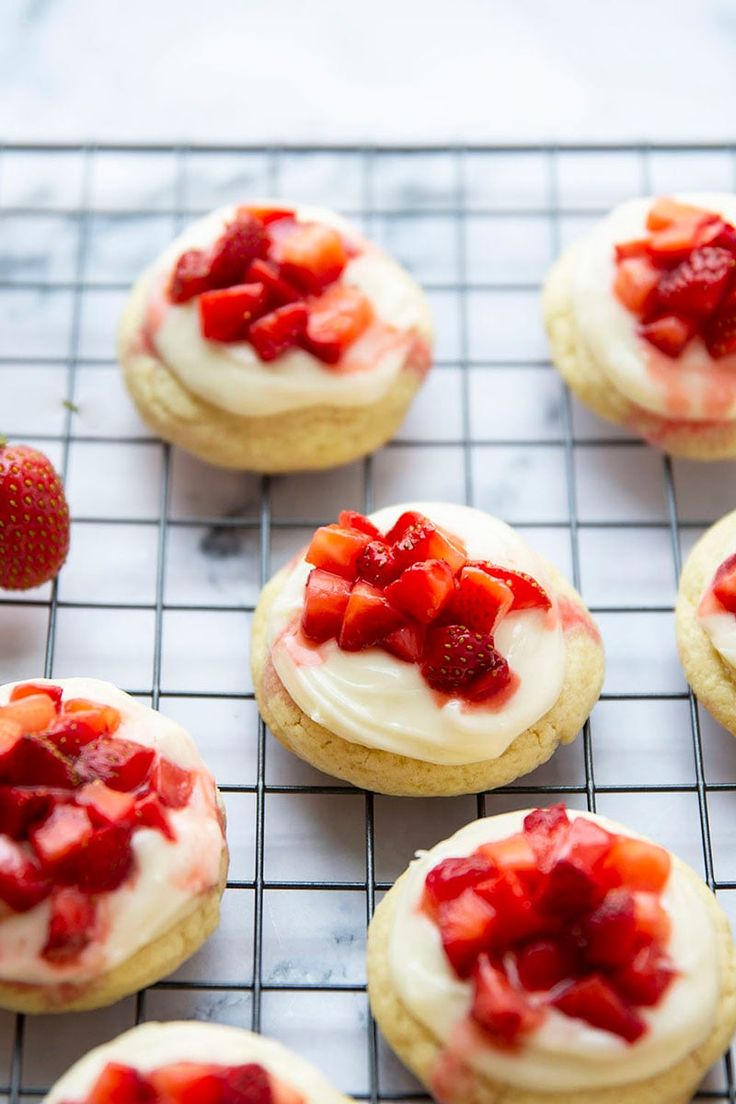 strawberry shortcakes with cream cheese frosting and strawberries arranged on a cooling rack