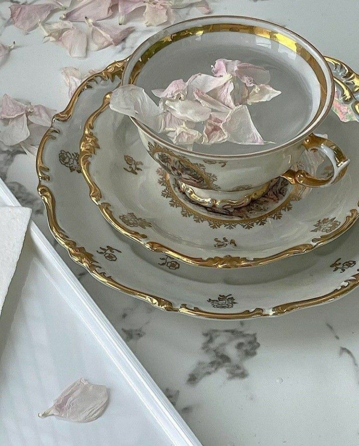 a cup and saucer sitting on top of a marble table with pink flowers in it