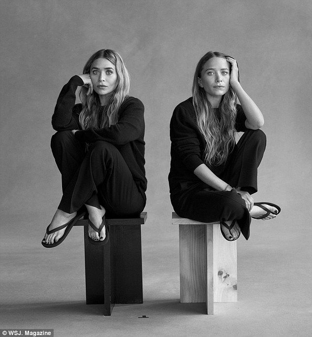 two women sitting on stools with their hands behind their heads, both looking at the camera