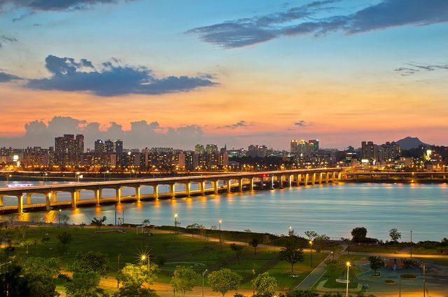 the city lights shine brightly in the distance as it sits next to a large body of water