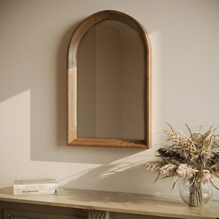 a vase filled with flowers sitting on top of a wooden table next to a mirror