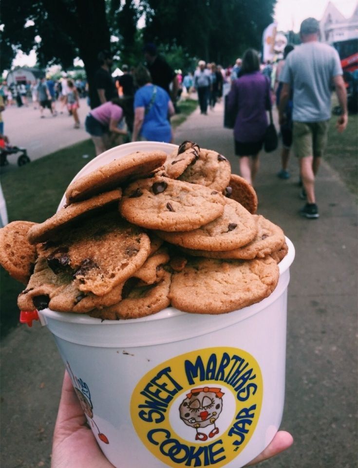 a cup filled with cookies and ice cream on top of a sidewalk next to people