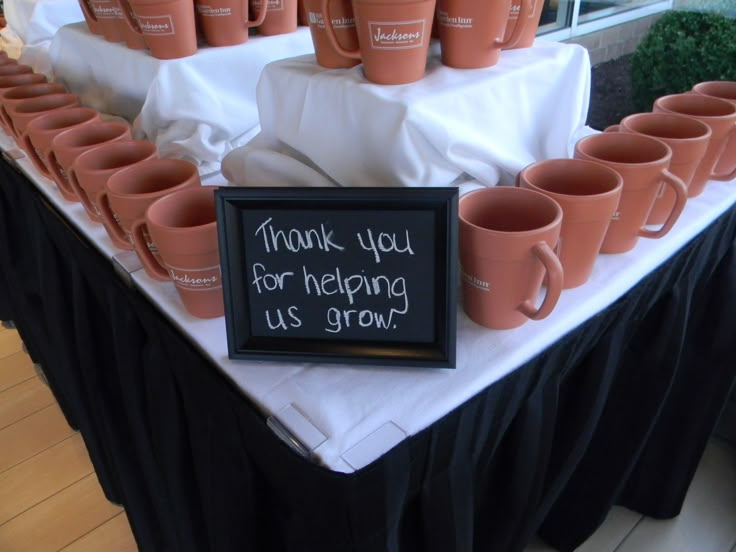 a table topped with lots of cups and a sign that says thank you for helping us grow