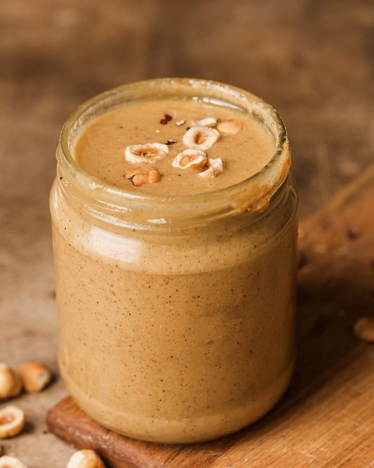 a jar filled with peanut butter on top of a wooden cutting board