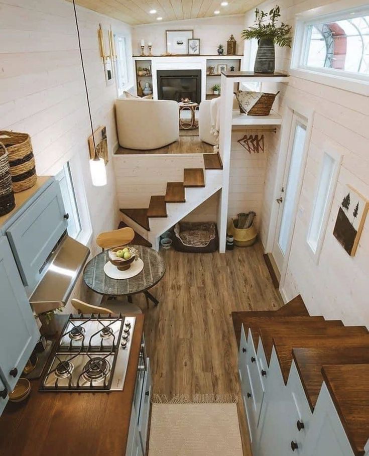 the interior of a tiny home with stairs leading up to the kitchen and living room