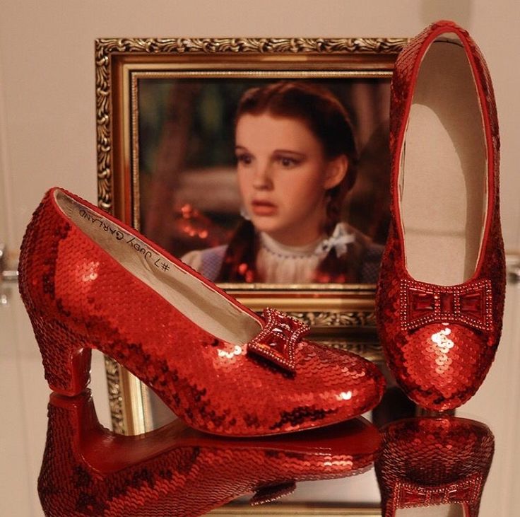 a pair of red shoes sitting on top of a table next to a framed photo