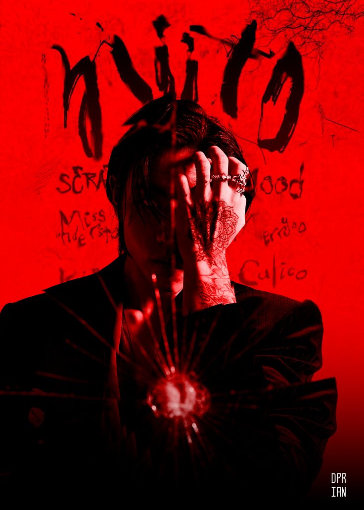 a man holding his hands to his face in front of a red wall with writing on it