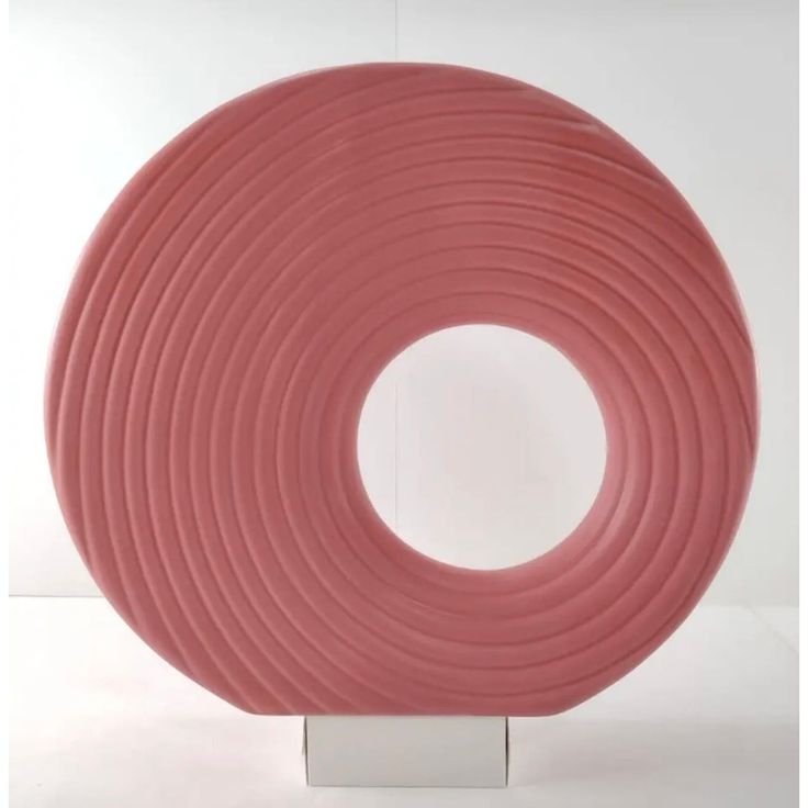 a pink sculpture sitting on top of a metal stand in front of a white wall