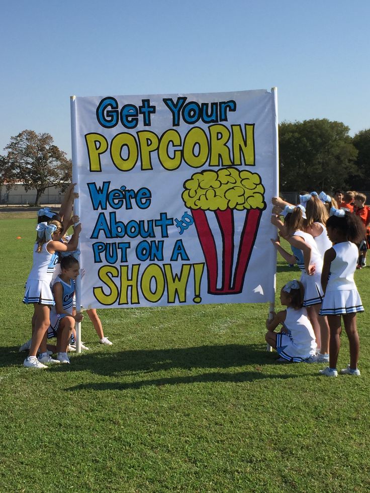 a group of girls holding up a sign that says get your popcorn we're about to put on a show