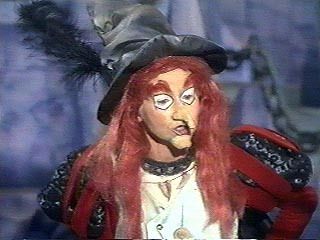 a close up of a person wearing a costume and hat with long red hair in front of a cat