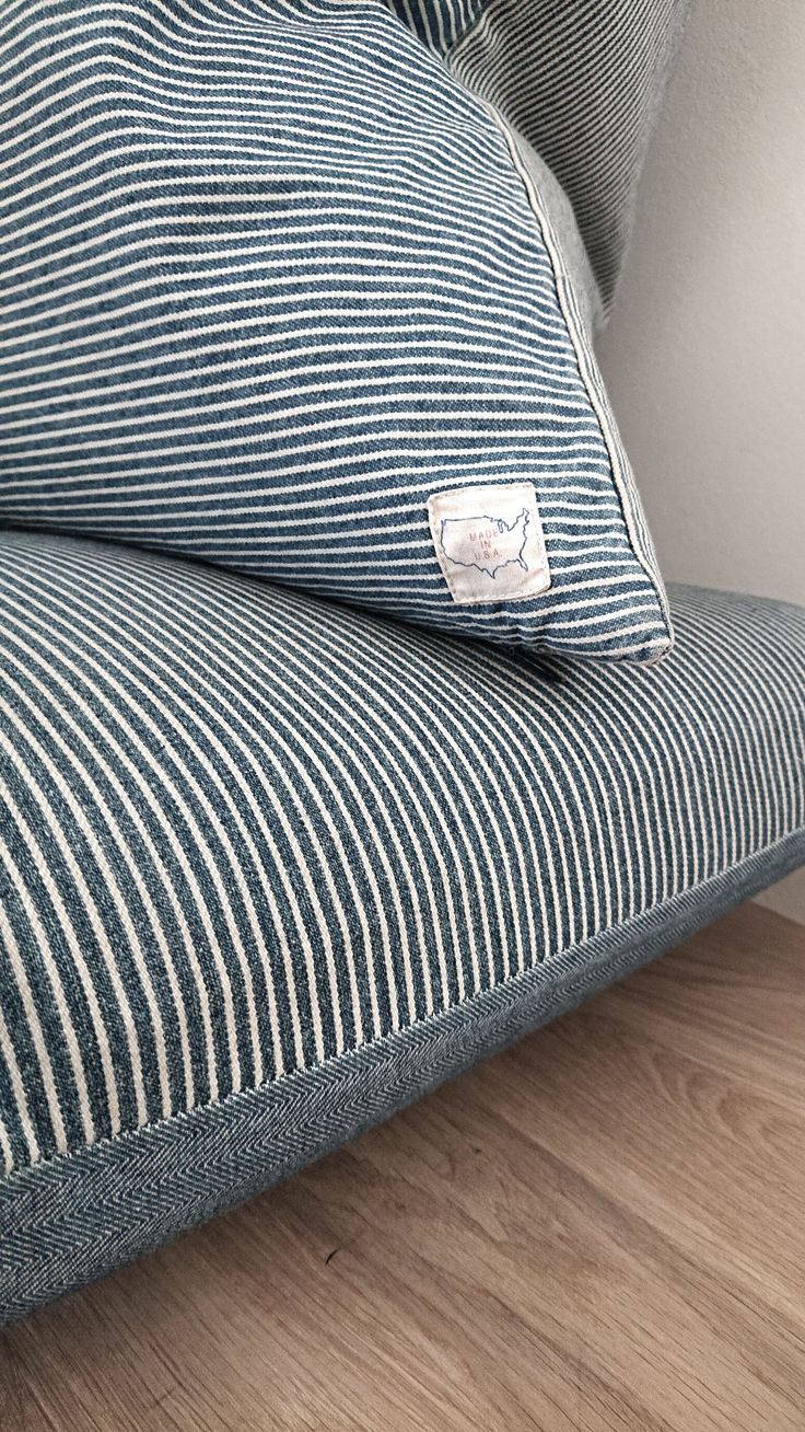 a blue and white striped couch sitting on top of a hard wood floor next to a wall