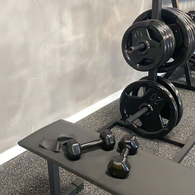 two black dumbbells sitting next to each other on top of a table in a gym