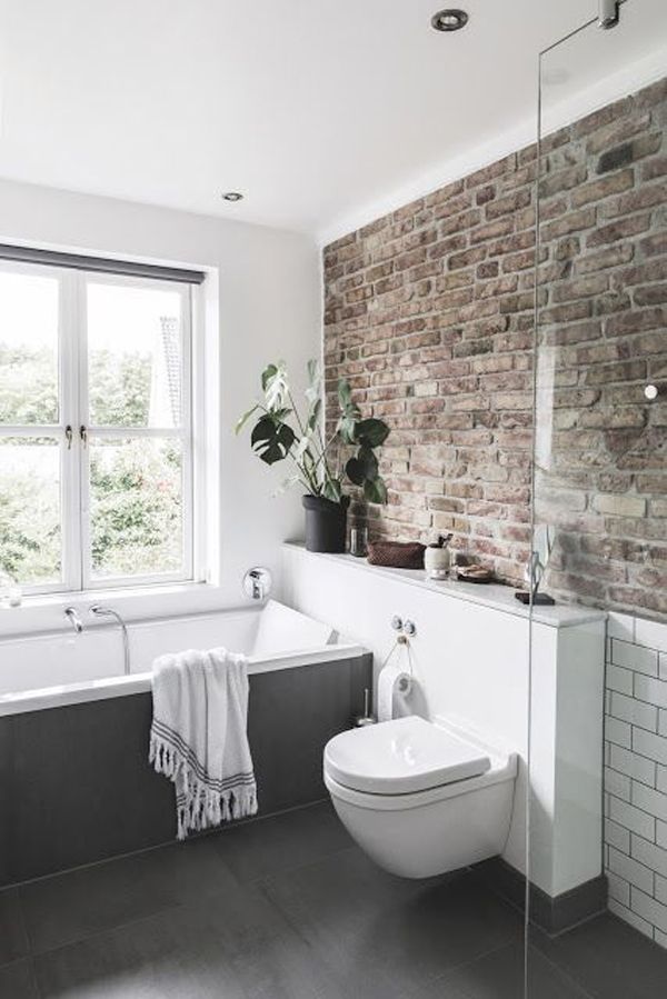 a bathroom with brick walls and white fixtures, including a tub, toilet and sink