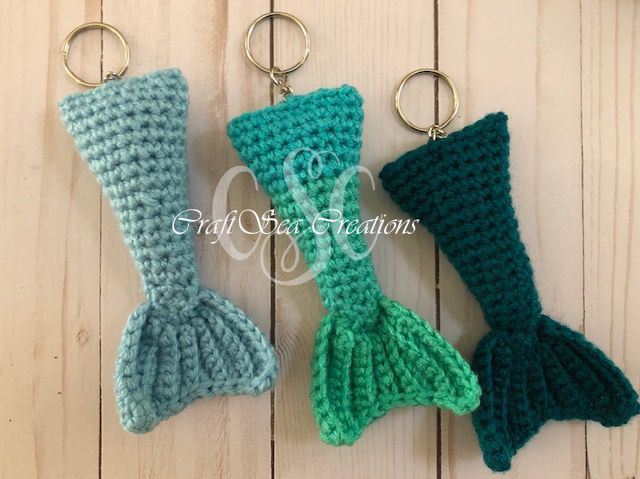 three crocheted mermaid tail keychains hanging from hooks