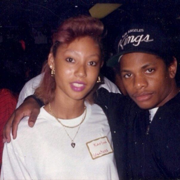 a man standing next to a woman in a white t - shirt and black hat