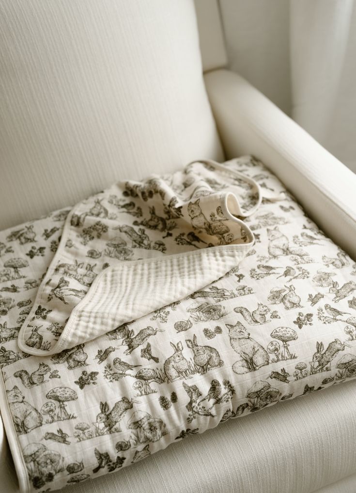 a white chair with a blanket on top of it next to a cup and saucer