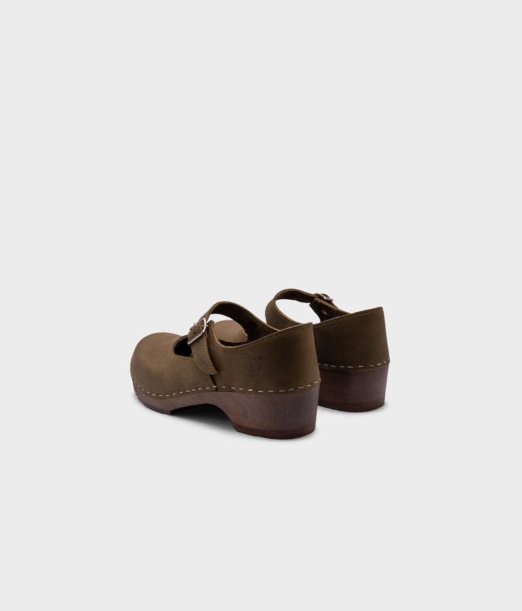 Mary Jane – the perfect blend of style and comfort. Handmade in Sweden, these low-heeled closed-back clogs are a must-have for any conscious customer looking to add sophistication to their wardrobe. With an undeniable cute factor, you'll feel confident and on-trend with every step. Clog measurements:Heel height: 1 3/4” (4.45 cm)Toe height: 1 5/8″ (4.1 cm)Fit:RegularLeather:Nubuck leatherClogs consist of:Base: European lime woodSole: Rubber soleFastening: StaplesOther: Metallic Buckle Mary Jane Clogs, Cork Sandals, Wooden Clogs, Clog Sandals, Boot Shop, Feel Confident, Low Heels, Mary Janes, Sweden