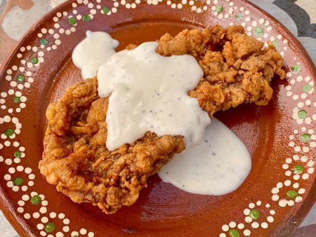 two fried chicken patties with ranch dressing on a brown and pink plate topped with sour cream