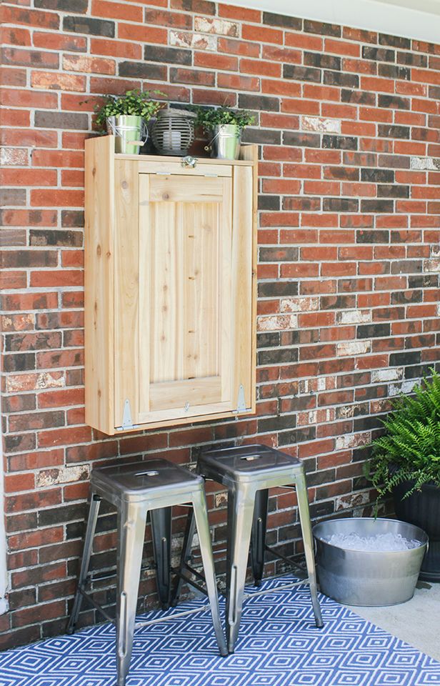 two metal stools sitting in front of a brick wall next to a potted plant