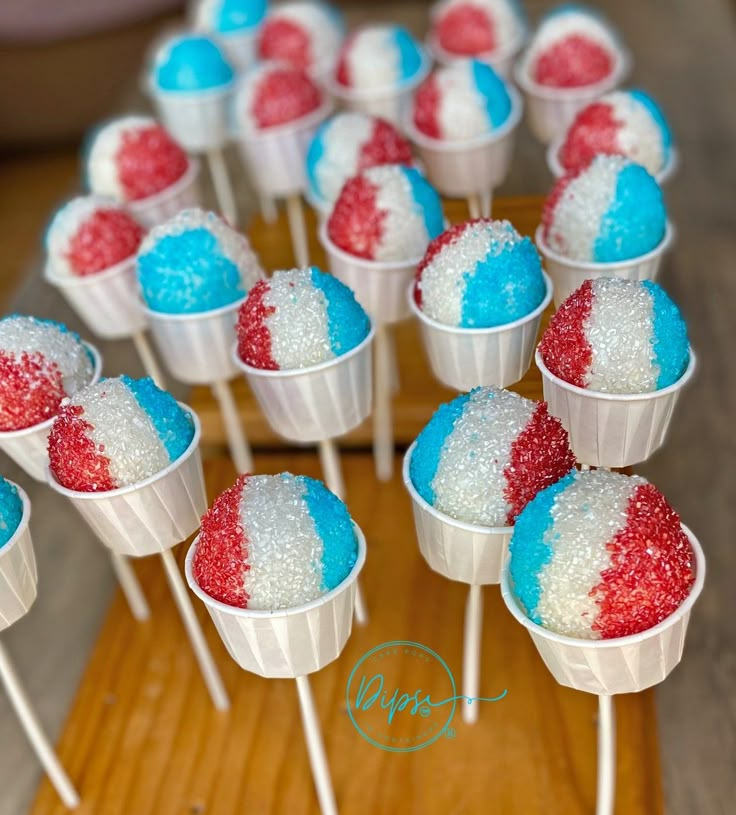 red, white and blue cupcakes in paper cups on a wooden tray with toothpicks