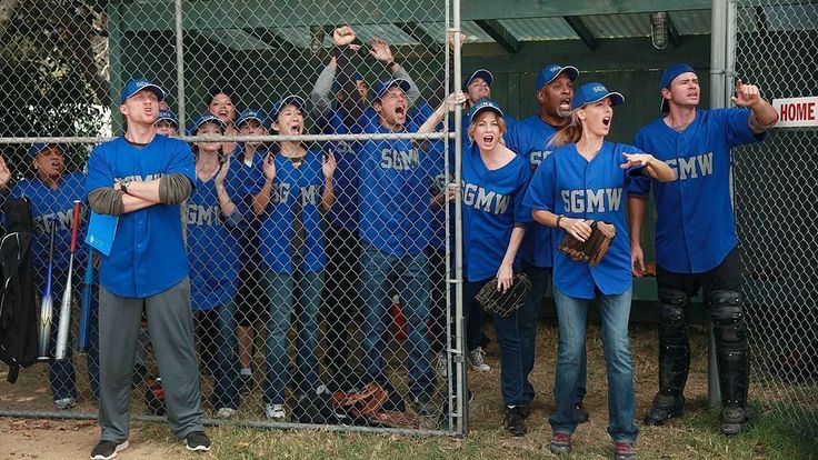 a group of people in blue baseball uniforms standing behind a fence with their hands up