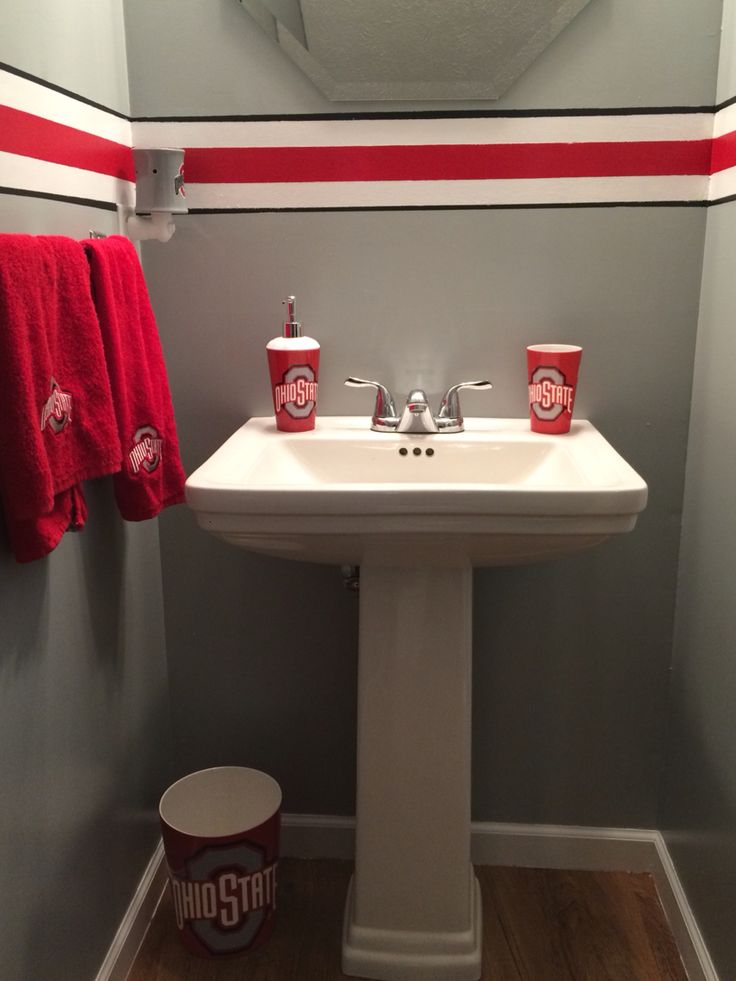 a bathroom with a sink, mirror and red towels hanging on the wall above it