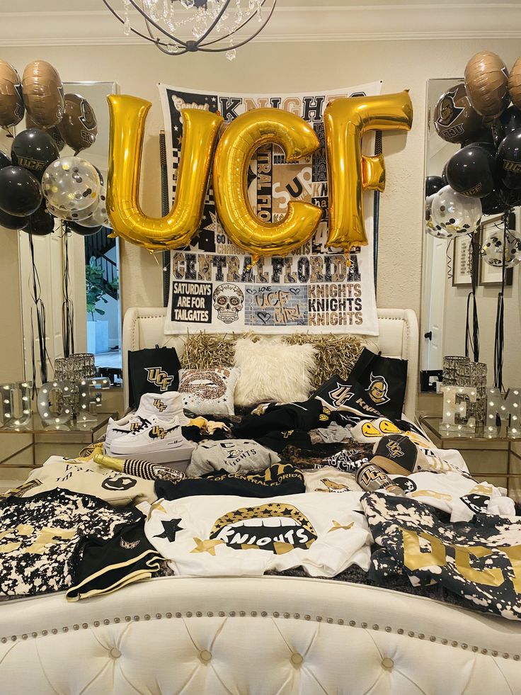 a bed with black and gold decorations on it in front of balloons that read ucf