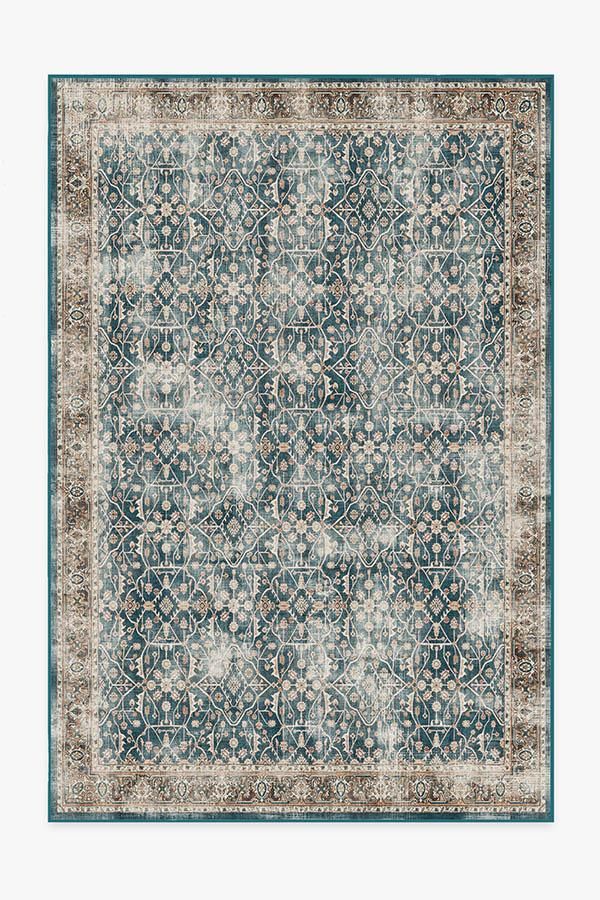 a blue and beige area rug with an ornate design on the center, in front of a white background