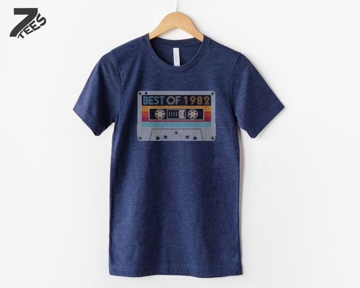 a blue t - shirt with the words best of 1989 printed on it, hanging on a wooden hanger