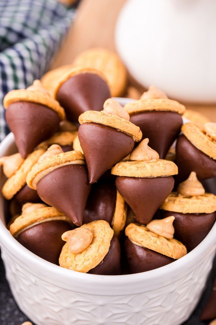 a white bowl filled with chocolate covered peanut butter cookies next to crackers on the table