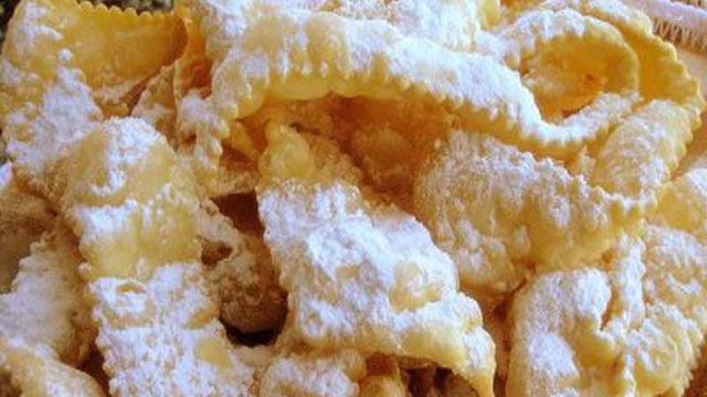 a pile of fried food sitting on top of a white plate covered in powdered sugar